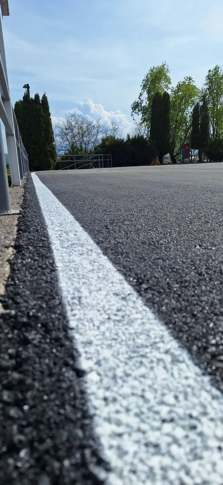 Detalj svježe nanesene bijele rubne linije na asfaltu